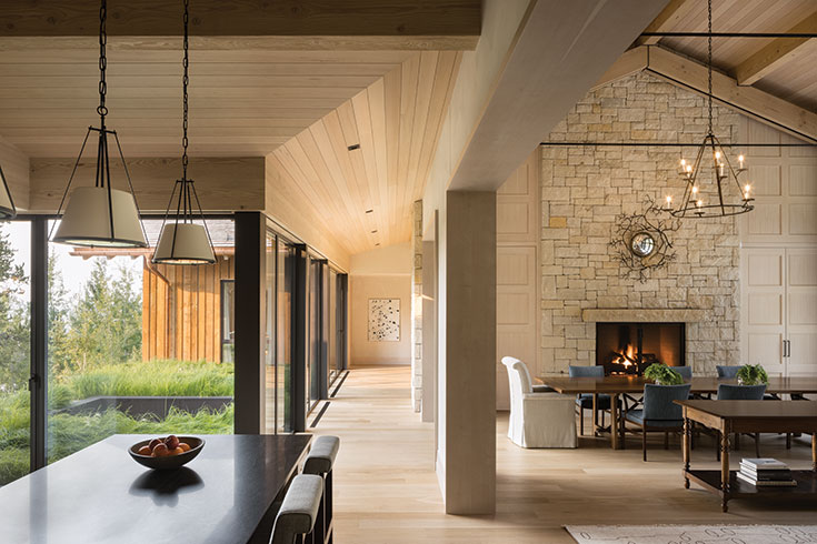 The great room presents options in relaxation that include fireside dining. Opening into the kitchen, and flanked on both sides by views into nature, the open feel makes for expansive living.