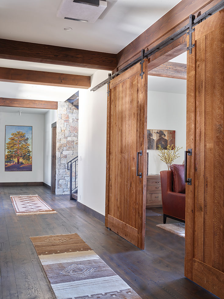 Artwork from Altamira Fine Art crowns the wide main hallway, punctuated by custom reclaimed barn doors delineating the office and downstairs lounge.