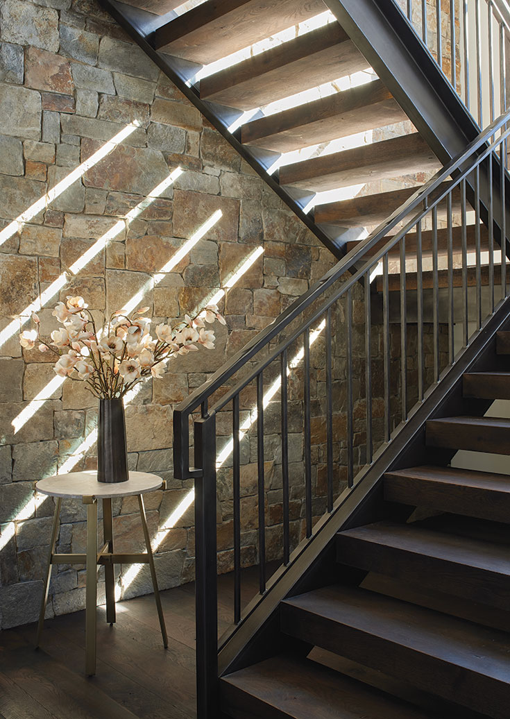 Chief cliff stone frames the custom gun-blued patinaed stairwell created by Heart Four Ironworks and accented by accessories from Belle Cose Home.